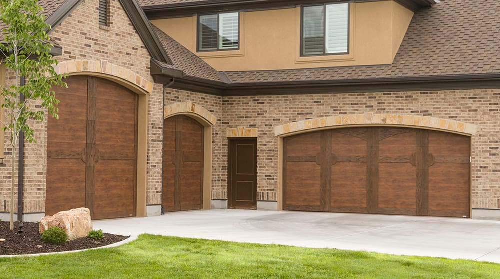 Wooden Chalet style garage doors on a brick home